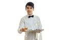 Handsome young waiter in a dress holding a tray with glasses of wine and smiling Royalty Free Stock Photo