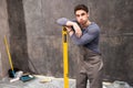 Handsome young worker leaning on level tool and looking at camera Royalty Free Stock Photo