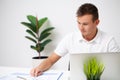 Handsome young worker working in a company office with documents and a laptop Royalty Free Stock Photo