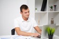 Handsome young worker working in a company office with documents and a laptop Royalty Free Stock Photo