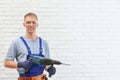 Handsome young working man with rotary hammer indoors. Home repair Royalty Free Stock Photo