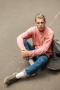 Handsome young youth man in a pink sweater with a skateboard