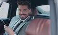 Happy young businessman using mobile phone in back seat of car Royalty Free Stock Photo