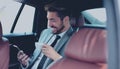 Happy young businessman using mobile phone in back seat of car Royalty Free Stock Photo