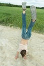 Handstand of teenage boy on dirt road at farm field background outdoors