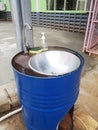 The handwashing basin is created by utilizing a blue oil drum, typically used for storing oil or other liquids. Royalty Free Stock Photo