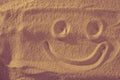 Handwrited face on the sand at the beach. Symbol smile on beach background