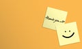 Handwriting of message thank you, heart shape and smile face on yellow sticky note on yellow background Royalty Free Stock Photo