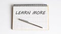 Handwriting text LEARN MORE on the notepad on white background Royalty Free Stock Photo