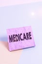 Handwriting text Medicare. Concept meaning the federal government plan in US for paying certain hospital Paper placed tilted above