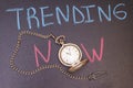 Handwriting trending now on chalkboard with colorful chalk and antique watch Royalty Free Stock Photo