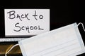 Handwritten Back to School lettered on white card with face mask and books