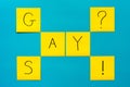 Handwritten black inscription gay and say on yellow square stickers on a blue background