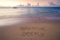 Handwritten Breathe deeply on sandy beach