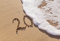 Handwritten inscription 20 on the sand with foamy wave Royalty Free Stock Photo