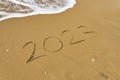 Handwritten Inscription on wet sand 2023 with sea foam and wave. Concept of fresh starts and expectations.