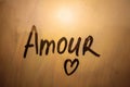 Lettering French text Amour is love in english written finger with heart shape on orange sunset window
