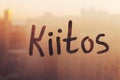 Finnish word Kiitos thanks in english are painted on wet orange sunrise glass of window Royalty Free Stock Photo