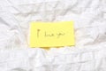 Handwritten little yellow note with the words I love you on white sheets on a bed, romantic concept valentines day