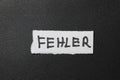 A handwritten note displaying the word FEHLER is placed on a textured black background, symbolizing error and communicat Royalty Free Stock Photo