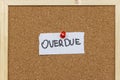 A handwritten note displaying the word OVERDUE pinned to a corkboard. The message indicates lateness or a deadline that Royalty Free Stock Photo