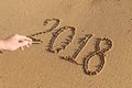 Handwritten numbers on the sand 2018 with male hand