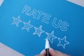 Handwritten review rate us and star rating on blue background Royalty Free Stock Photo