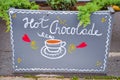 Handwritten sign hot chocolate and simple drawing of the cup with a drink on an outside flowerpot. Original advertisements