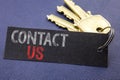 Handwritten text showing Contact Us. Business concept writing for Customer Support Written on note paper attached to the key, blac