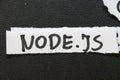 Handwritten text on a torn paper strip displaying NODE.JS. Node.js is a JavaScript runtime built on Chromes V8 engine, c Royalty Free Stock Photo