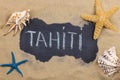 Handwritten word TAHITI written in chalk, among seashells and starfishes