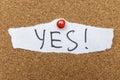 A handwritten YES! on a torn piece of white paper pinned to a corkboard. The message conveys affirmation and commitment, Royalty Free Stock Photo