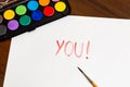 Handwritten YOU text with brush and watercolor paints on white background. Box of watercolor paints with a brush for drawing Royalty Free Stock Photo