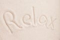 Handwritting word RELAX in sand above view macro
