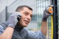 handy man measuring metal fence while calling on phone