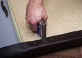 Handy man upholstering paricle board using leather, staples and