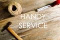 Handy service written on wooden background with rope,hammer and measuring tape