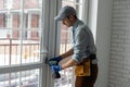 handyman adjusting white pvc plastic window indoors. worker using screwdriver to repair upvc window. homework