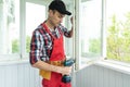 handyman adjusting white pvc plastic window indoors. worker using screwdriver to repair upvc window. homework