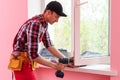 handyman adjusting white pvc plastic window indoors. worker using screwdriver to repair upvc window. homework