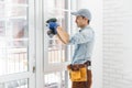 handyman adjusting white pvc plastic window indoors. worker using screwdriver to repair upvc window. homework