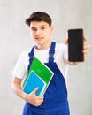 Unfocused handyman in jumpsuit with large stack of notebooks shows dark empty mobile phone screen