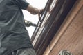 A handyman or carpenter drilling small rivet holes into the gutter of a roof. Using a power electric drill Royalty Free Stock Photo