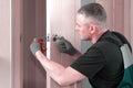 Handyman carpenter installs an internal door lock. Wooden interior door