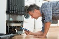 Handyman Checking Refrigerator With Flashlight At Home Royalty Free Stock Photo