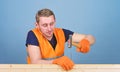 Handyman concept. Man, handyman in working uniform and protective gloves handcrafting with hammer, light blue background Royalty Free Stock Photo