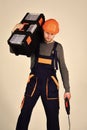 Handyman concept. Man in overall and helmet holds toolbox on shoulder and drill in hand. Strong and attractive repairer