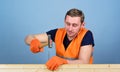 Handyman concept. Man, handyman in working uniform and protective gloves handcrafting with hammer, light blue background