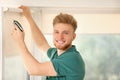 Handyman with cordless screwdriver installing roller window blind