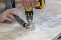 handyman cut round holes for electrical outlets in the marble countertop for the kitchen using a hand drill Royalty Free Stock Photo